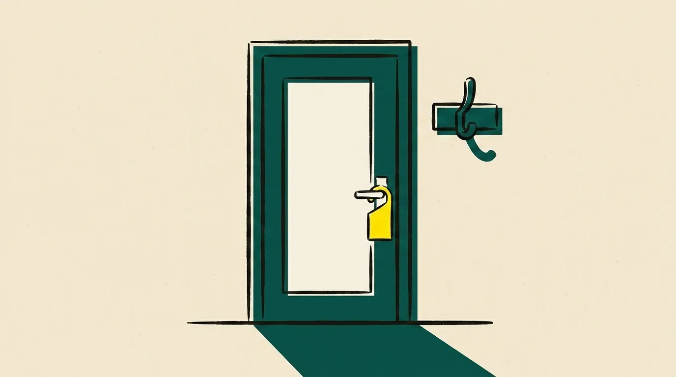 A door with a name tag hanging on the handle and a coat hook beside it